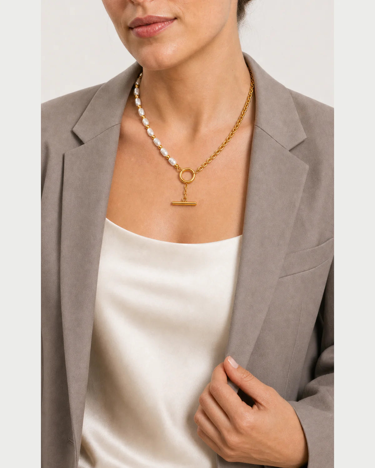 Model holding her blazer lapel while wearing the Amélie necklace