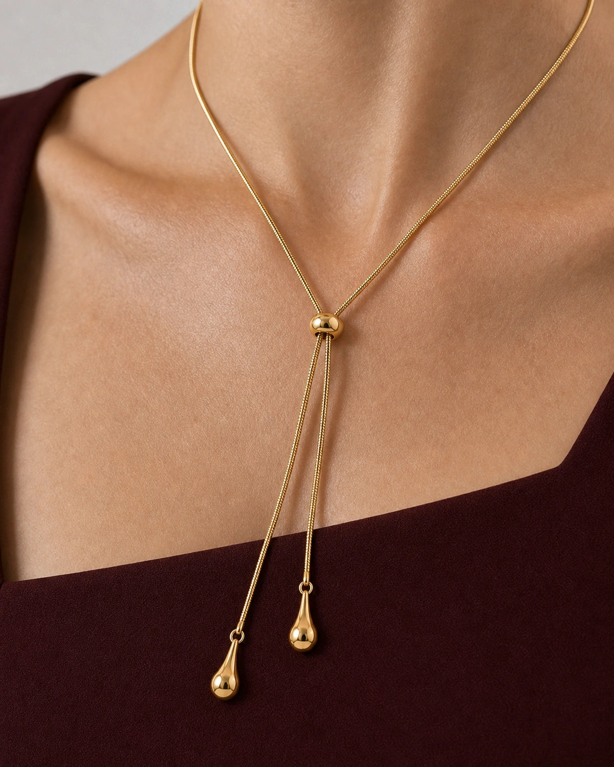 Complete worn macro of the Aurelia snake-chain lariat and two teardrop charms