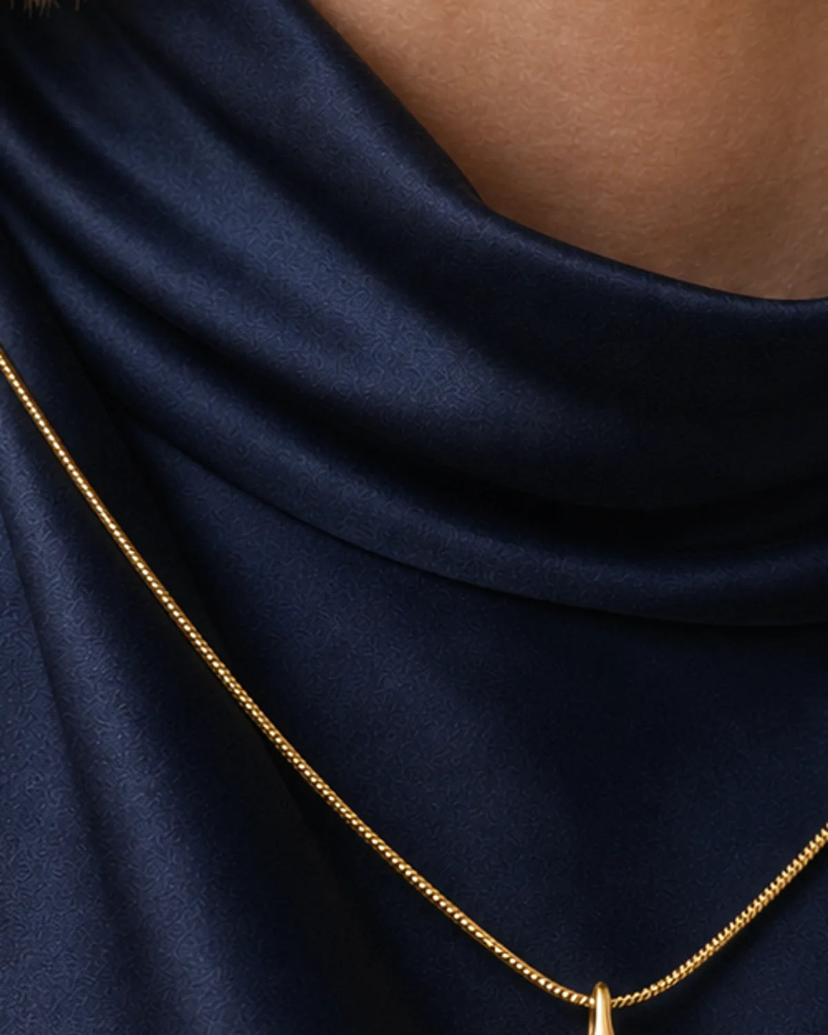 Extreme worn macro of the Elara gold recessed droplet and polished snake chain