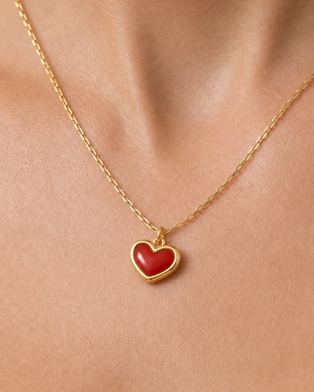 Extreme on-body macro of the Estelle red enamel heart and gold chain