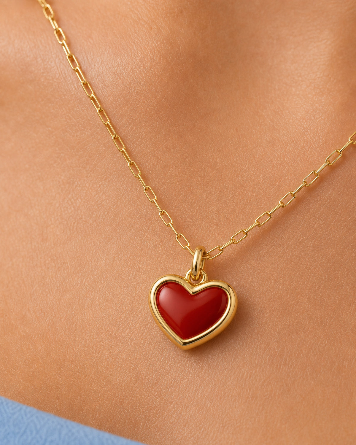 Extreme worn macro of the Estelle red enamel heart, gold border, bail and rectangular-link chain