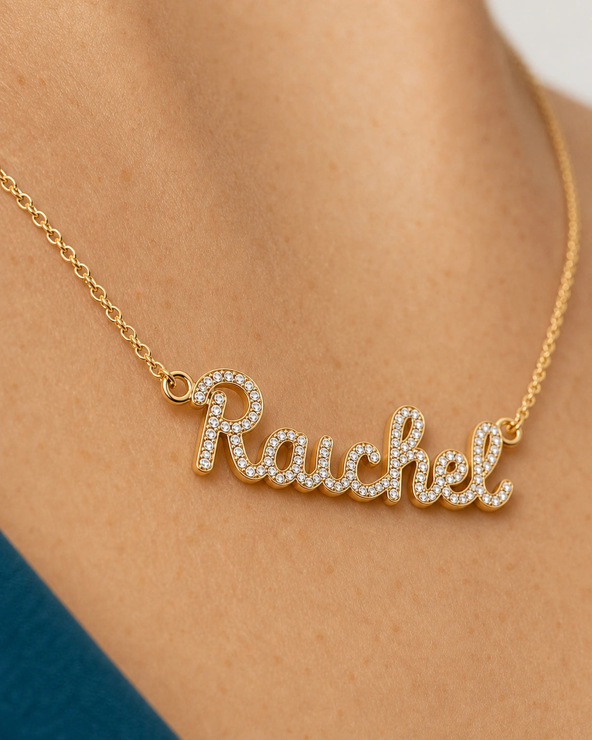 Oblique worn macro of the gold Mira pavé Rachel lettering and side-loop connection