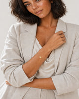 Australian model aged 25 to 28 wearing the Amara initial A bracelet in a pale dove-grey studio