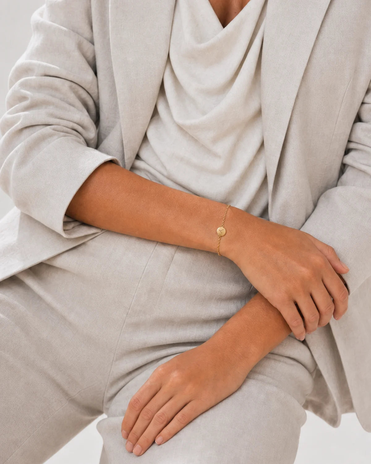 Human-scale styling detail of the Amara initial A bracelet with ivory tailoring