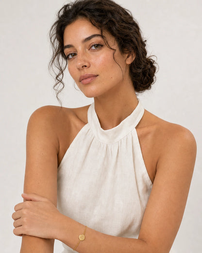 Model in an ivory Amalfi linen halter dress wearing the Amara initial A bracelet