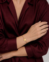 Amara gold initial bracelet worn in a crossed-hands pose