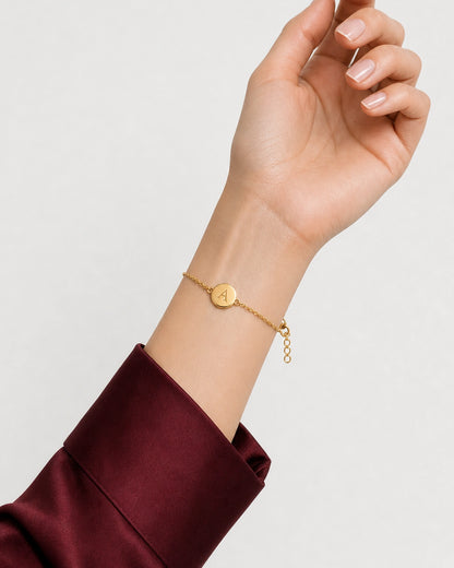 Amara gold initial bracelet shown in a palm-up wearing pose
