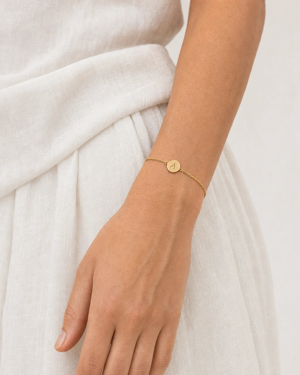 Close wearing view of the Amara domed serif A disc and fine gold chain