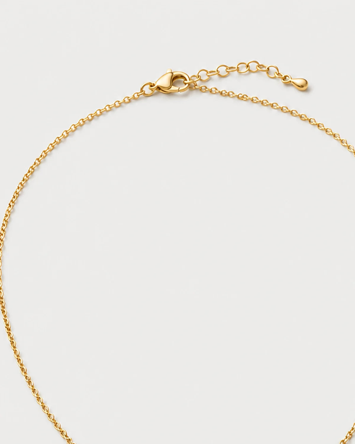 Clasp and extender detail of the Amara initial medallion necklace on pale dove-grey