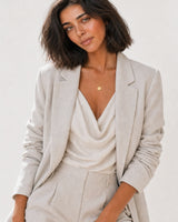Wide editorial portrait showing the Amara initial medallion necklace at natural scale