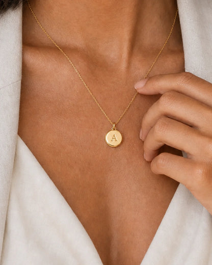 Extreme on-body macro of the Amara engraved A medallion and fine gold chain