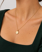 Jewellery-led neckline detail of the gold Amara serif-A medallion