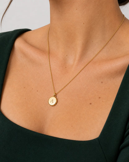 Jewellery-led neckline detail of the gold Amara serif-A medallion