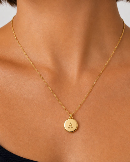 On-body macro of the Amara polished gold medallion and centered serif A