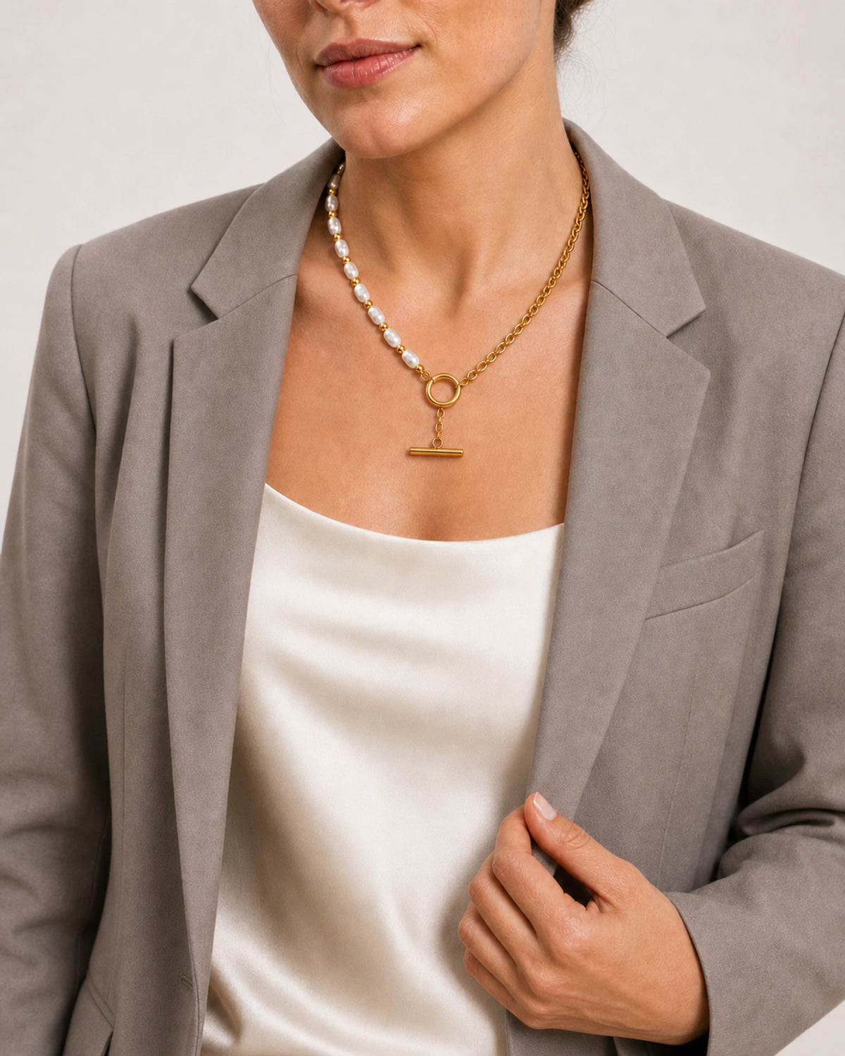 Model holding her blazer lapel while wearing the Amélie necklace