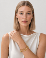 Model wearing the Amorette gold charm bracelet in a pale dove-grey studio