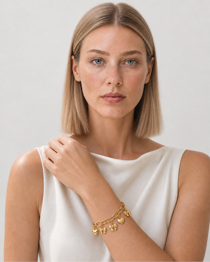 Model wearing the Amorette gold charm bracelet in a pale dove-grey studio