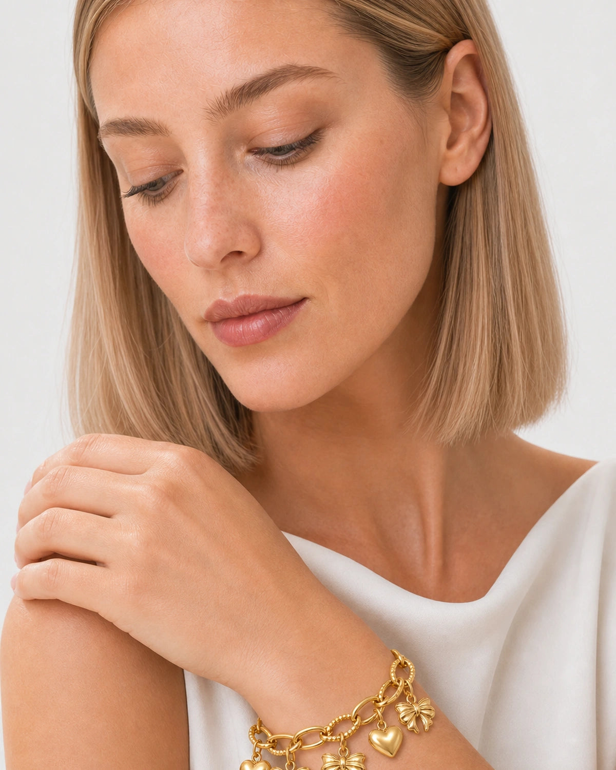 Close wrist view of the Amorette gold heart and bow charm bracelet