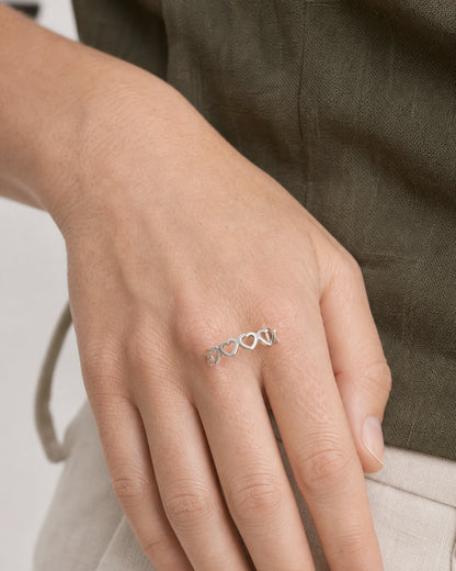 Close hand portrait showing the Amoura silver open-heart band