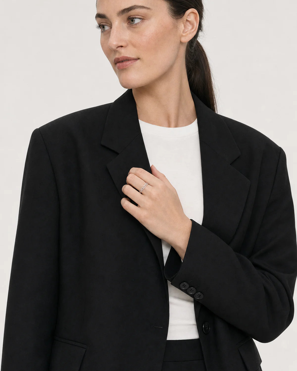 Wide grey-studio editorial portrait featuring the Amoura silver ring
