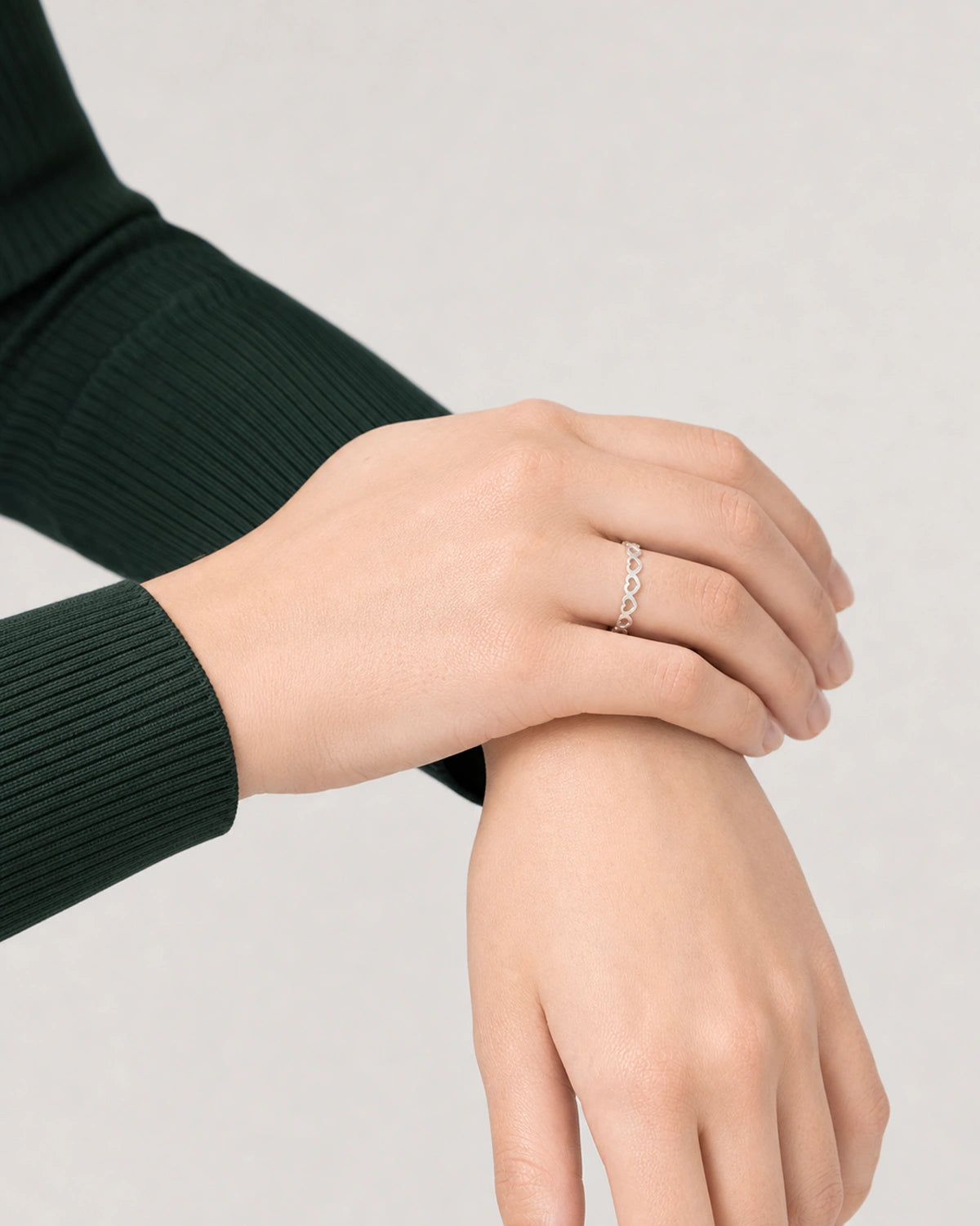 Crossed-wrist editorial hand pose featuring the silver Amoura open-heart ring