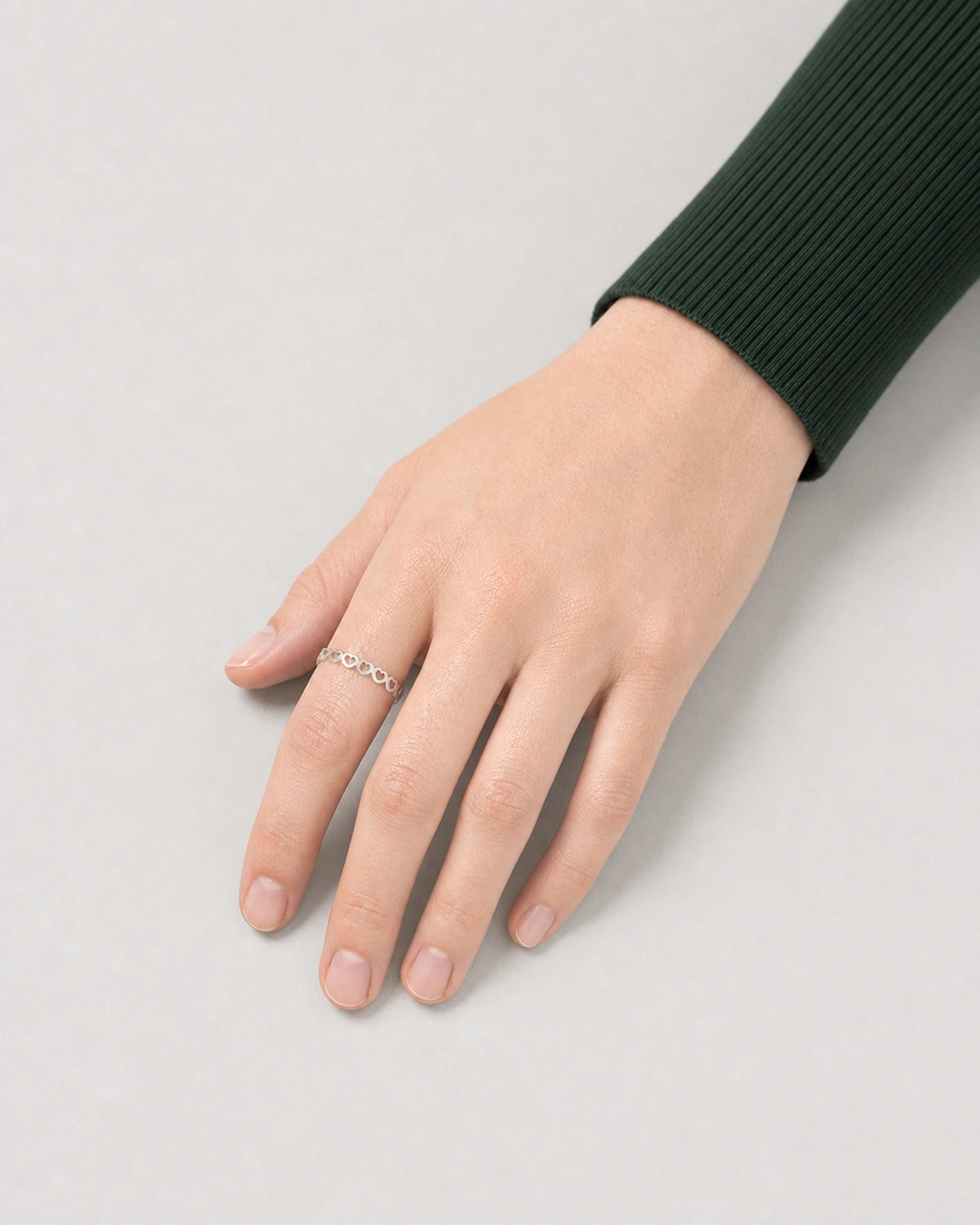 Top-down hand view of Camille wearing the slim silver Amoura heart ring