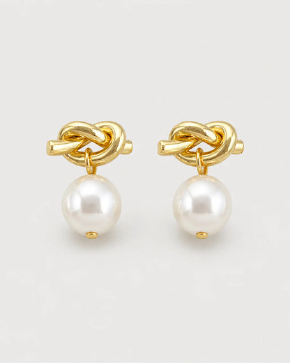 Apolline gold knot pearl drop earrings on pale dove-grey