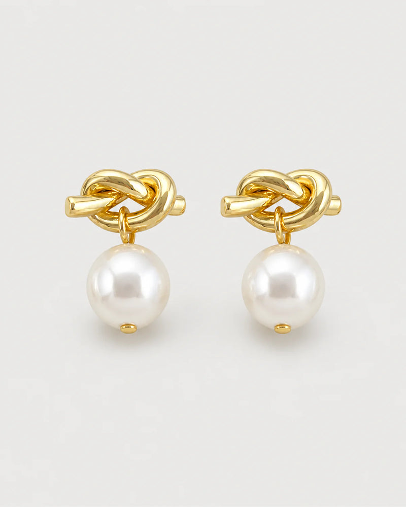 Apolline gold knot pearl drop earrings on pale dove-grey