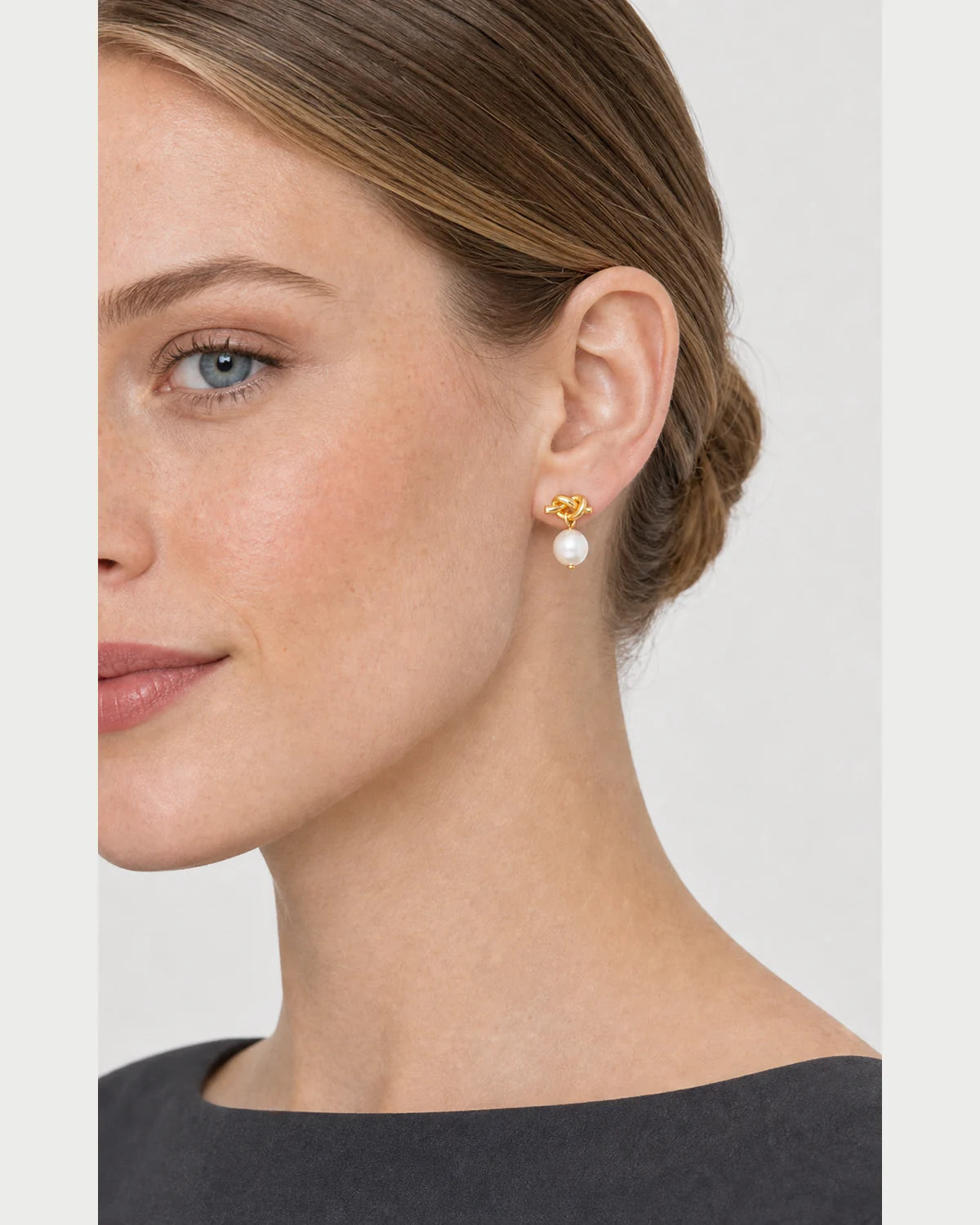 Close side portrait showing the Apolline gold knot pearl earring