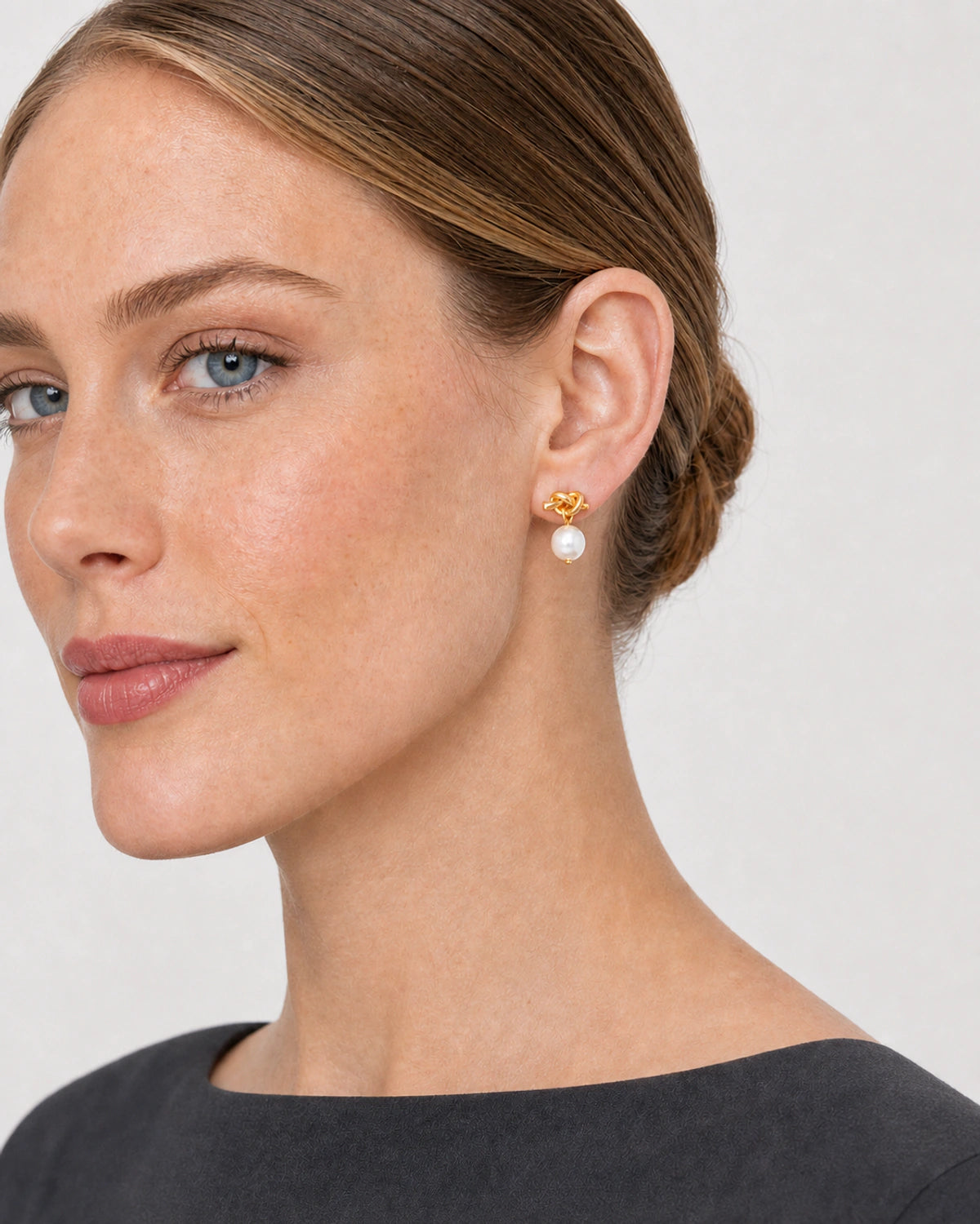 Close side portrait showing the Apolline gold knot pearl earring