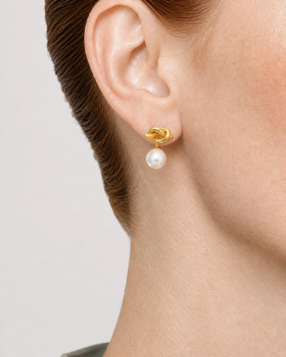 Complete worn macro of the gold Apolline love-knot and pearl drop on Laurel
