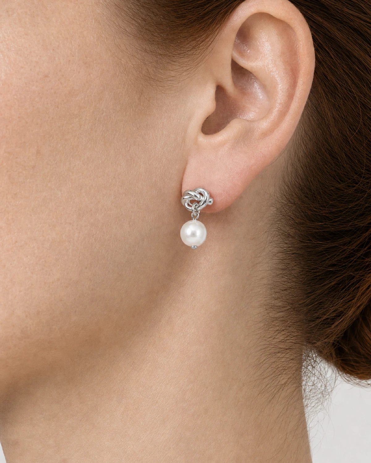 Complete rear-side worn macro of the silver Apolline knot pearl earring