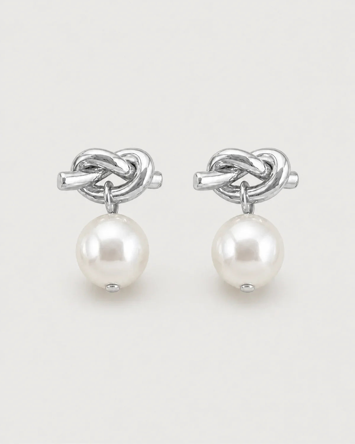 Apolline silver knot pearl drop earrings on pale dove-grey