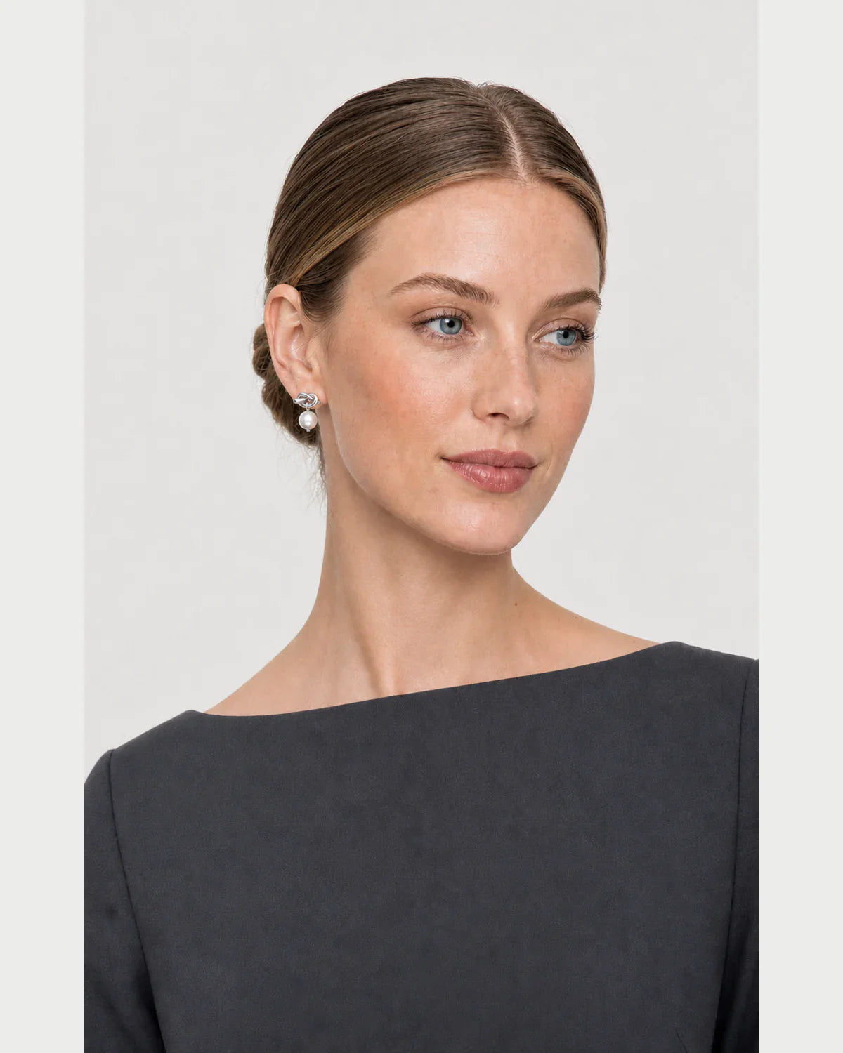 Three-quarter studio portrait featuring the silver Apolline pearl earrings