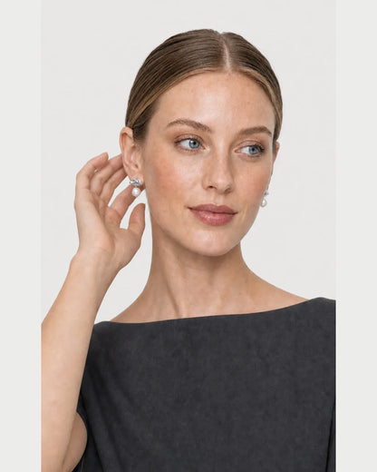 Human-scale portrait with a hand gesture beside the silver Apolline earring