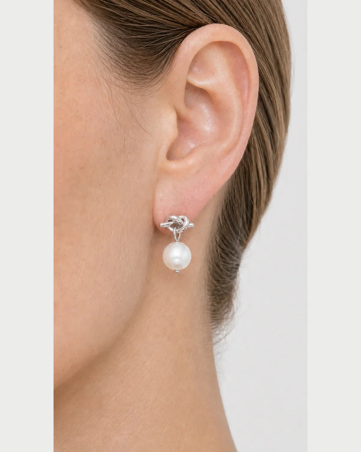 Extreme on-ear macro of the Apolline silver knot and pearl drop