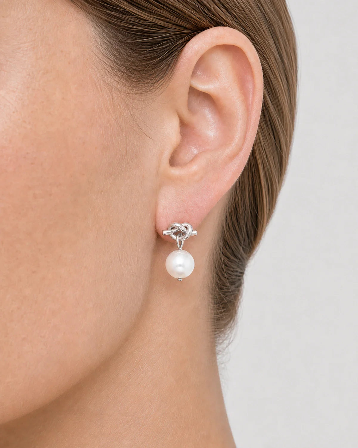 Extreme on-ear macro of the Apolline silver knot and pearl drop