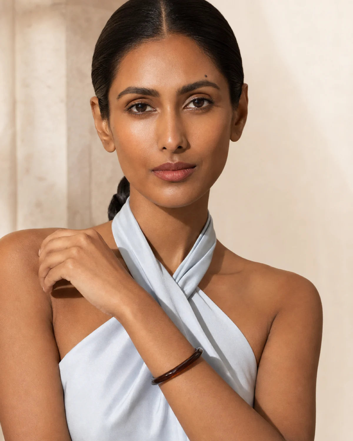 Model in powder-blue satin wearing the Arden espresso bangle with a direct gaze