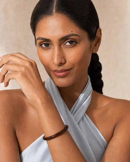 Model holding the Arden espresso resin bangle beside her face at true scale