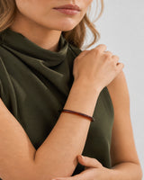 Mouth-down crossed-wrist view of Lucy wearing the espresso Arden Slim Resin Bangle
