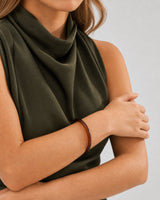 Supported forearm view of Lucy wearing the slim espresso Arden resin bangle