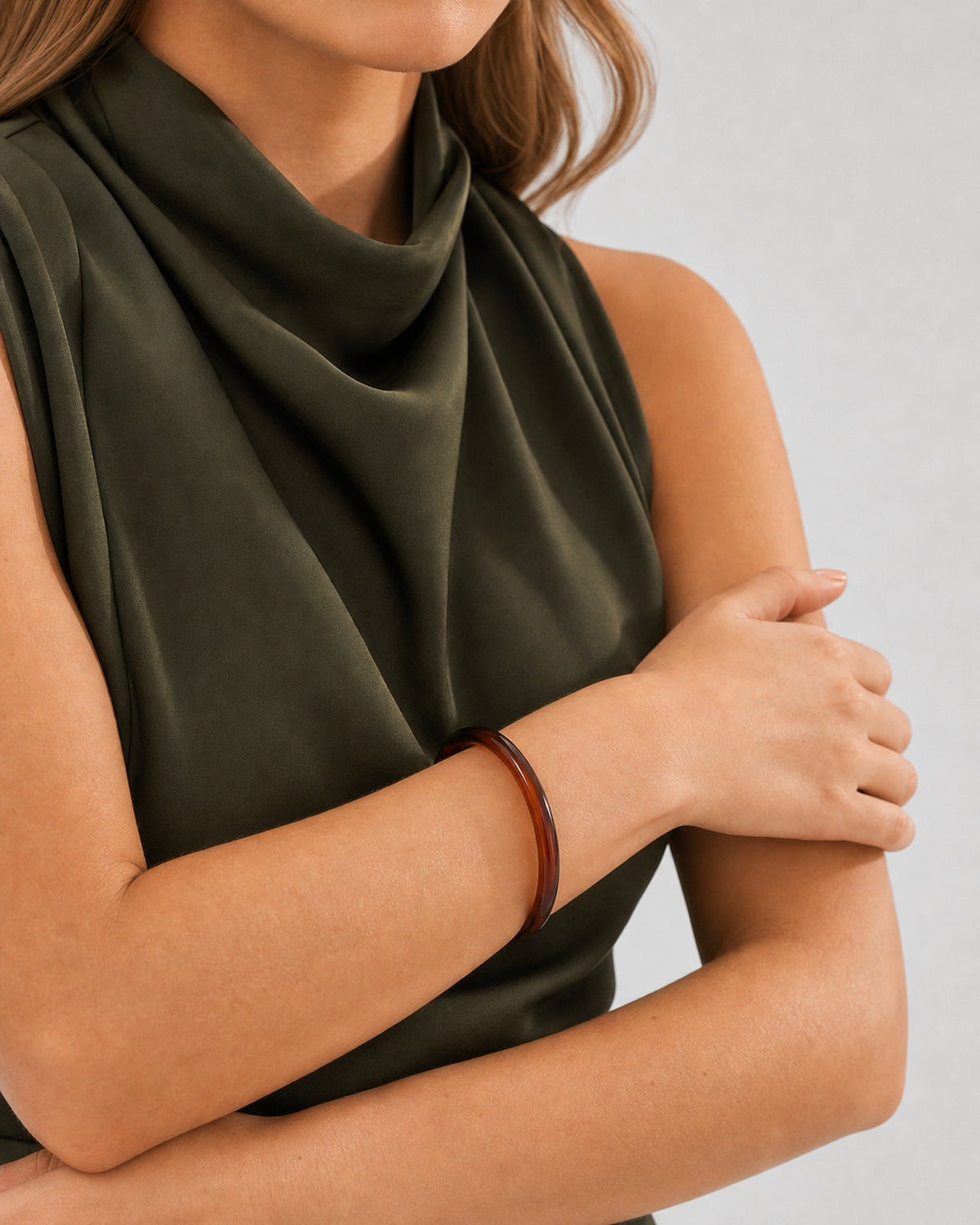 Supported forearm view of Lucy wearing the slim espresso Arden resin bangle