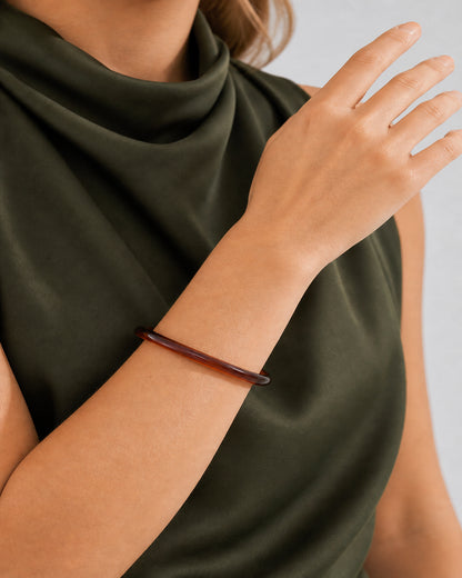 Mouth-down raised-wrist detail of the translucent espresso Arden bangle