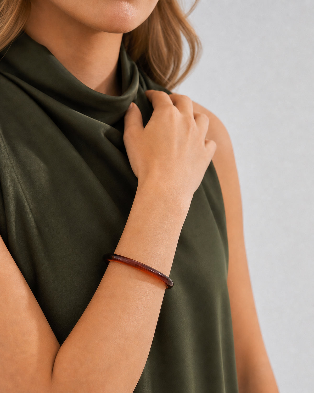 Chin-down collarbone pose showing the slim profile of the espresso Arden bangle