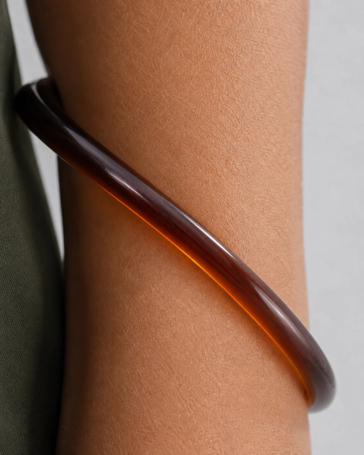 Extreme worn macro showing the translucent espresso construction of the Arden bangle