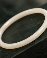 Macro of the polished Arden ivory resin bangle on deep green stone