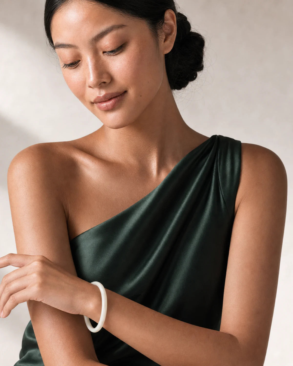 Clean wrist close-up of the Arden ivory bangle with the model looking down