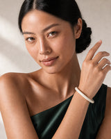 Model holding the Arden ivory resin bangle beside her face at true scale