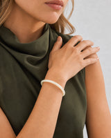 Mouth-down crossed-wrist view of Lucy wearing the ivory Arden Slim Resin Bangle