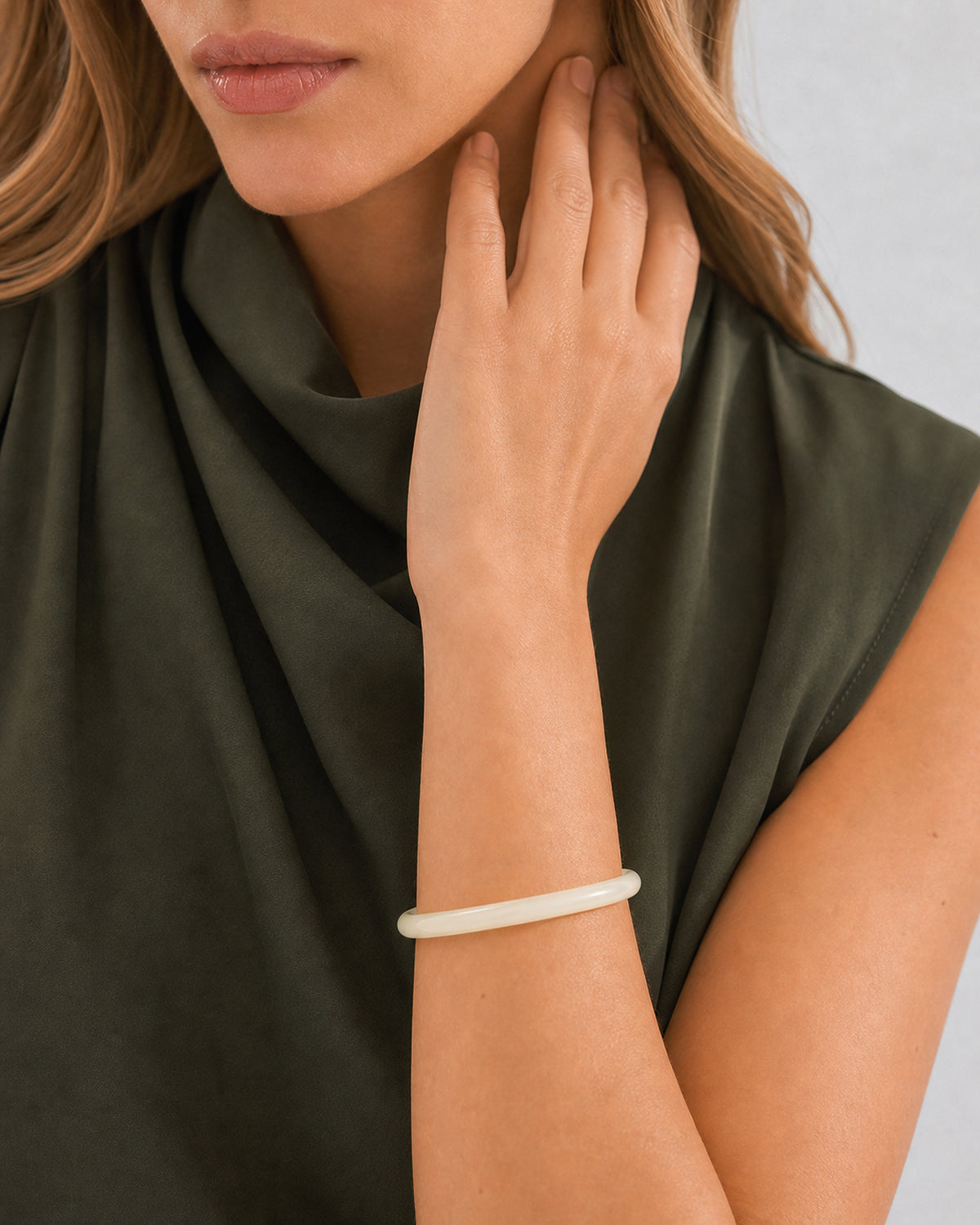 Mouth-down raised-wrist detail of the pearlescent ivory Arden bangle